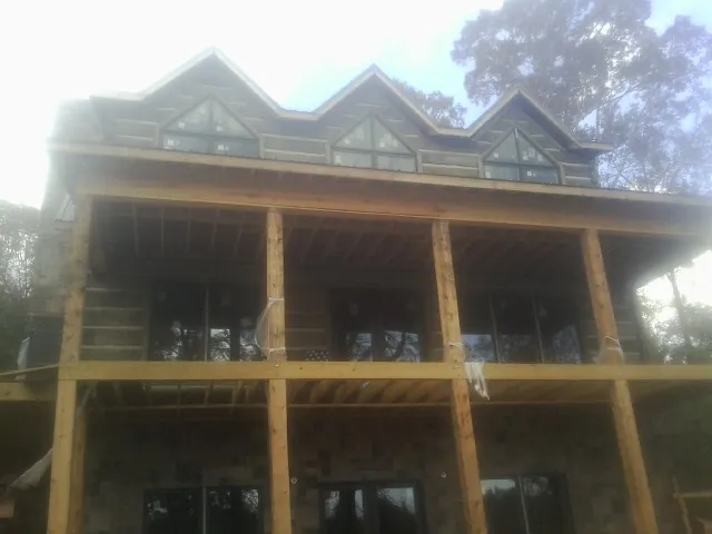 Dormers and porch framing on a large log home under construction — Roof Coating work by our crew in Rockaway Park