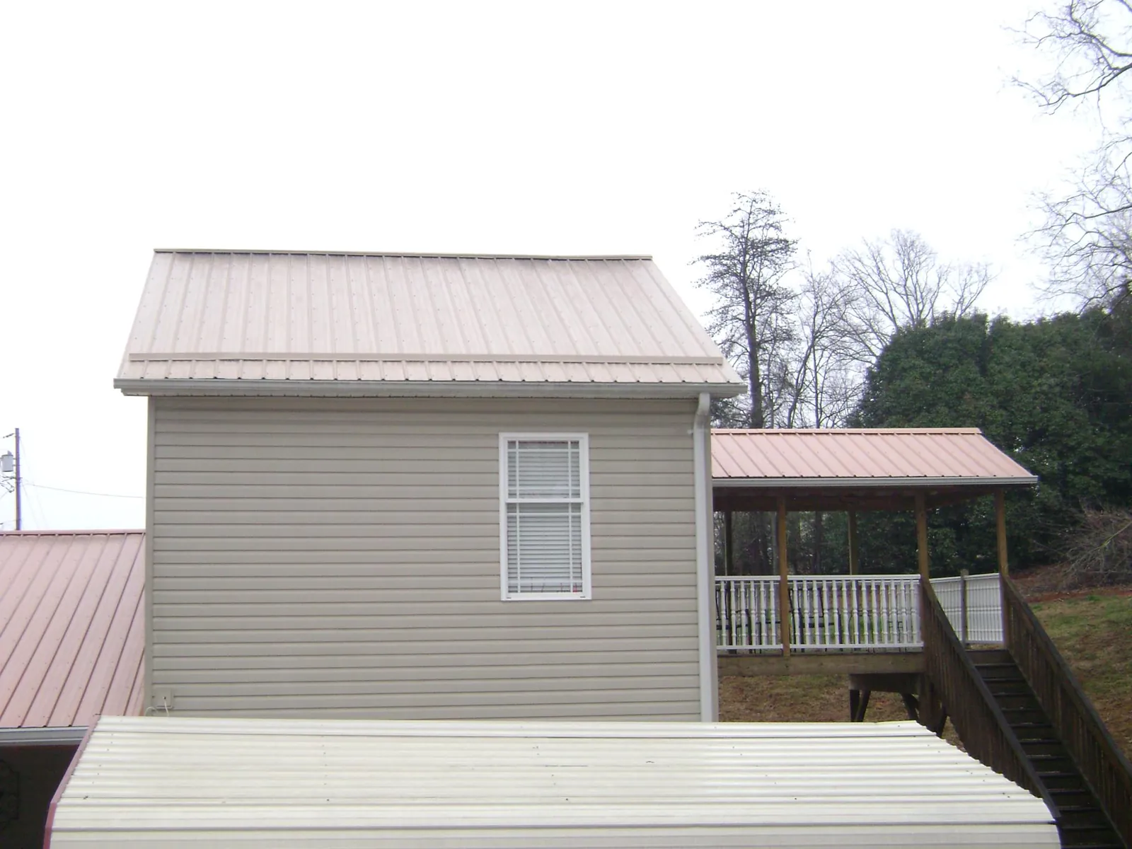 Tan metal roofs on a two story addition and attached porch, from a Roof Replacement job in Rockaway Park