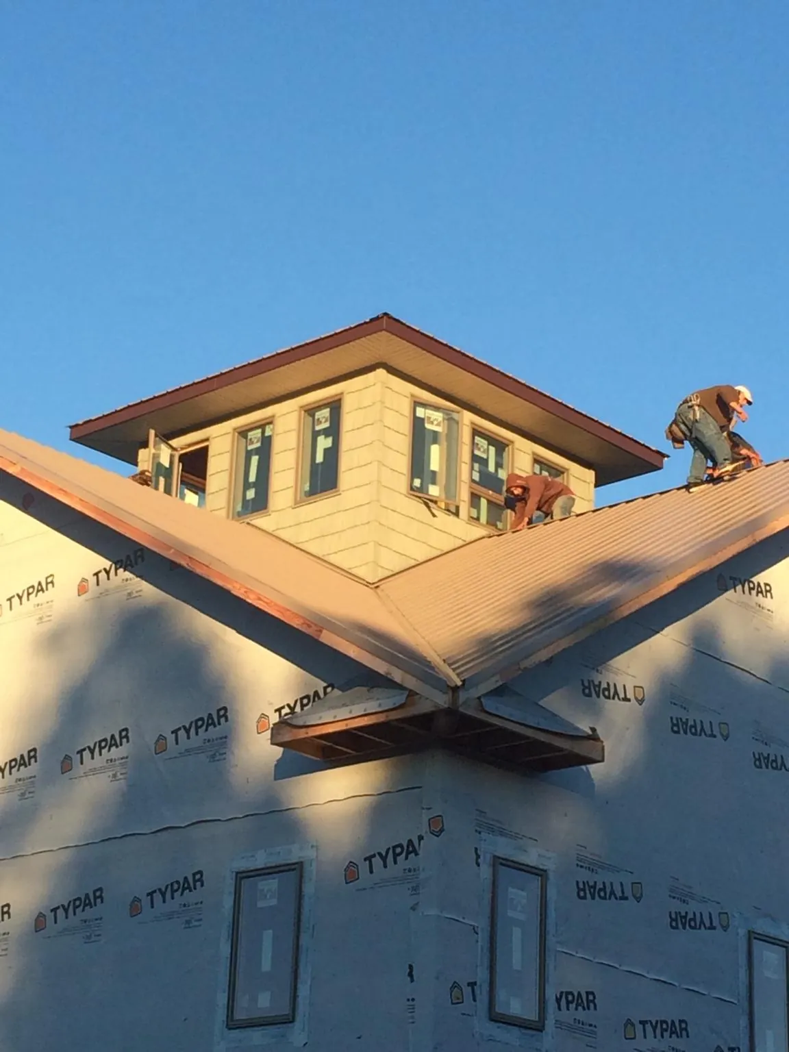 Roofers working around a rooftop cupola on a new metal roof at sunset — Roof Waterproofing in Rockaway Park by Roofing Brothers